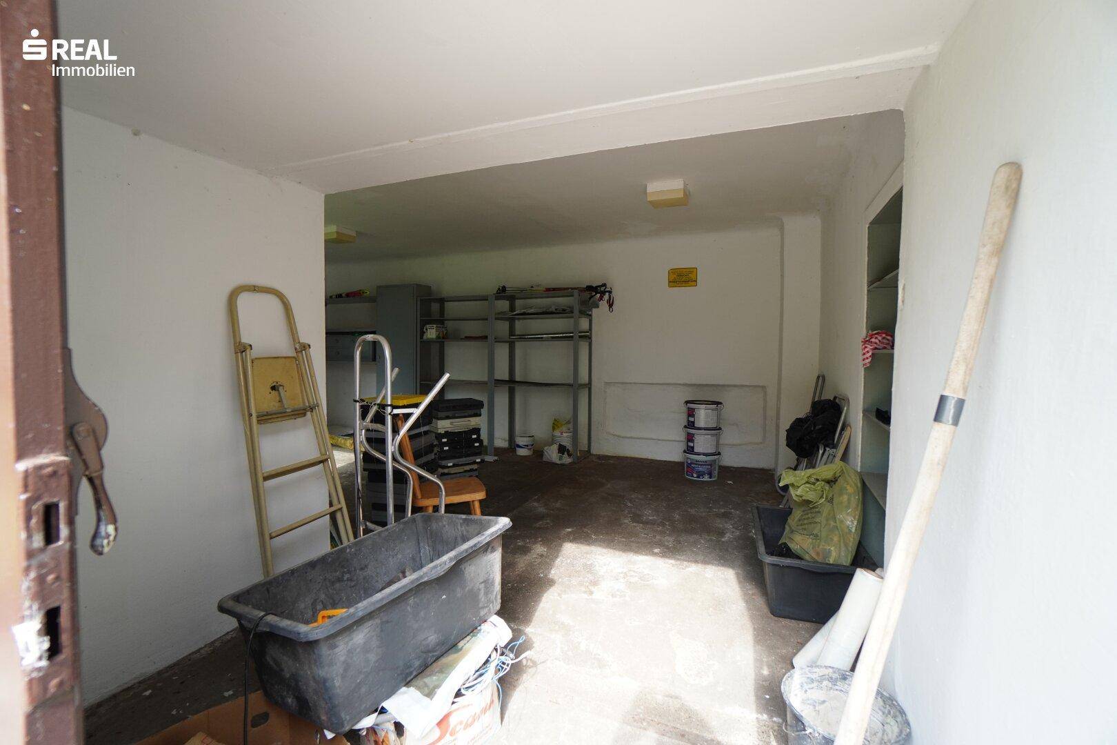 Innenansicht der Garage mit viel Stauraum und Regalen, direkt zugänglich.