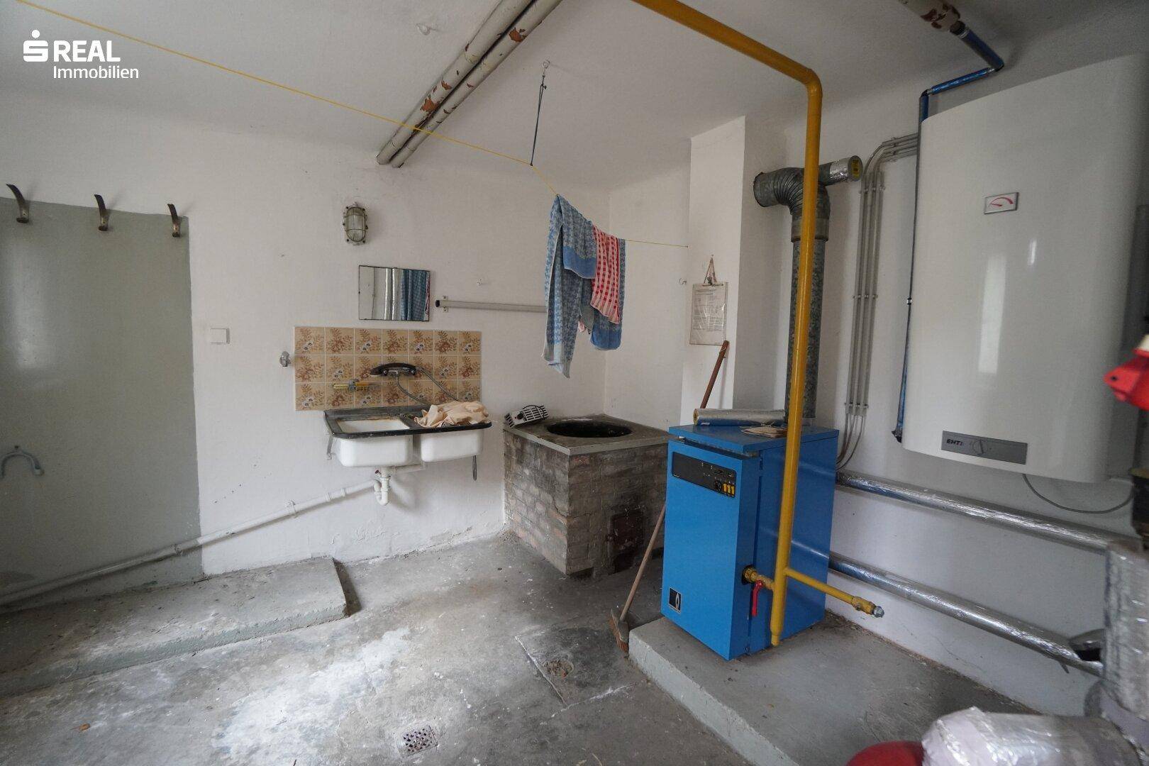 Hauswirtschaftsraum mit Heizungsanlage, Waschbecken und sichtbaren Installationen.