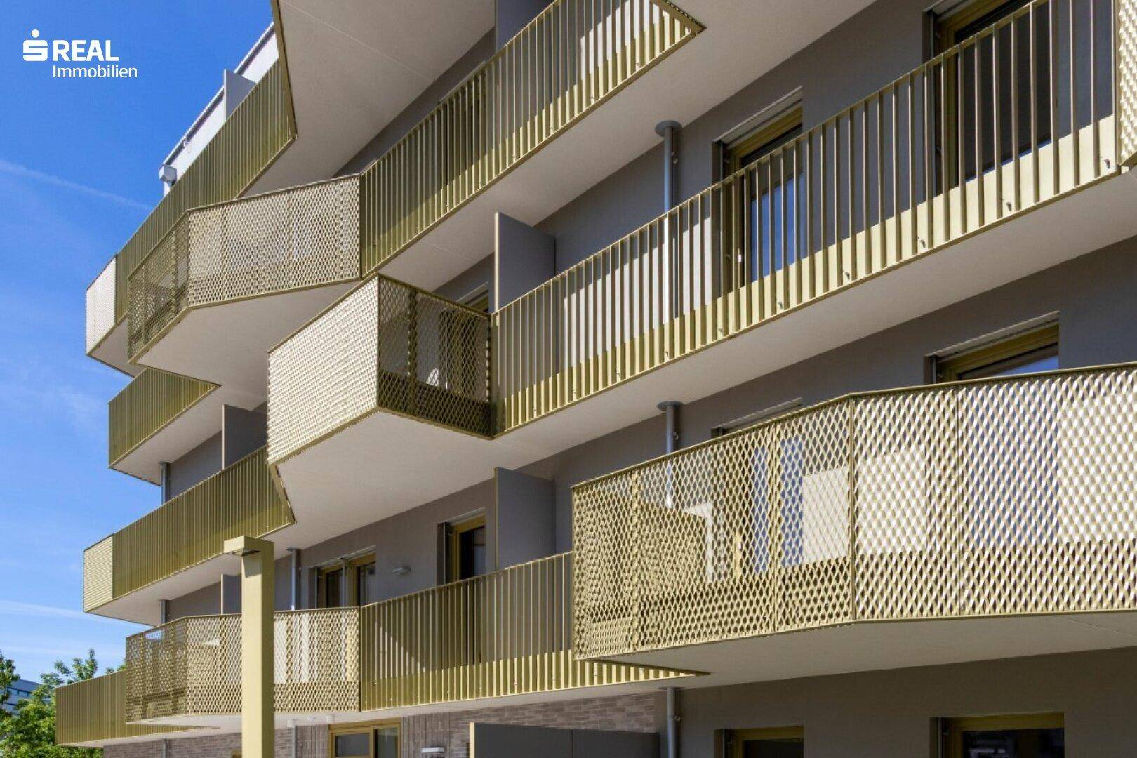 Nahaufnahme der modernen Balkone mit vertikalen und perforierten goldfarbenen Geländern.