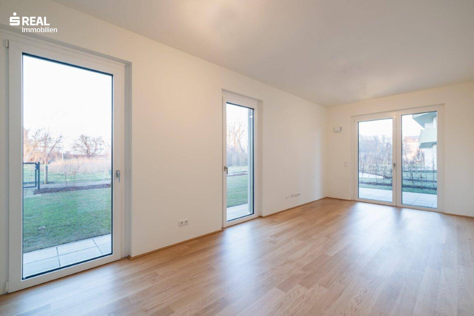 Lichtdurchfluteter Raum mit mehreren Fenstertüren und Zugang zu einem Außenbereich.