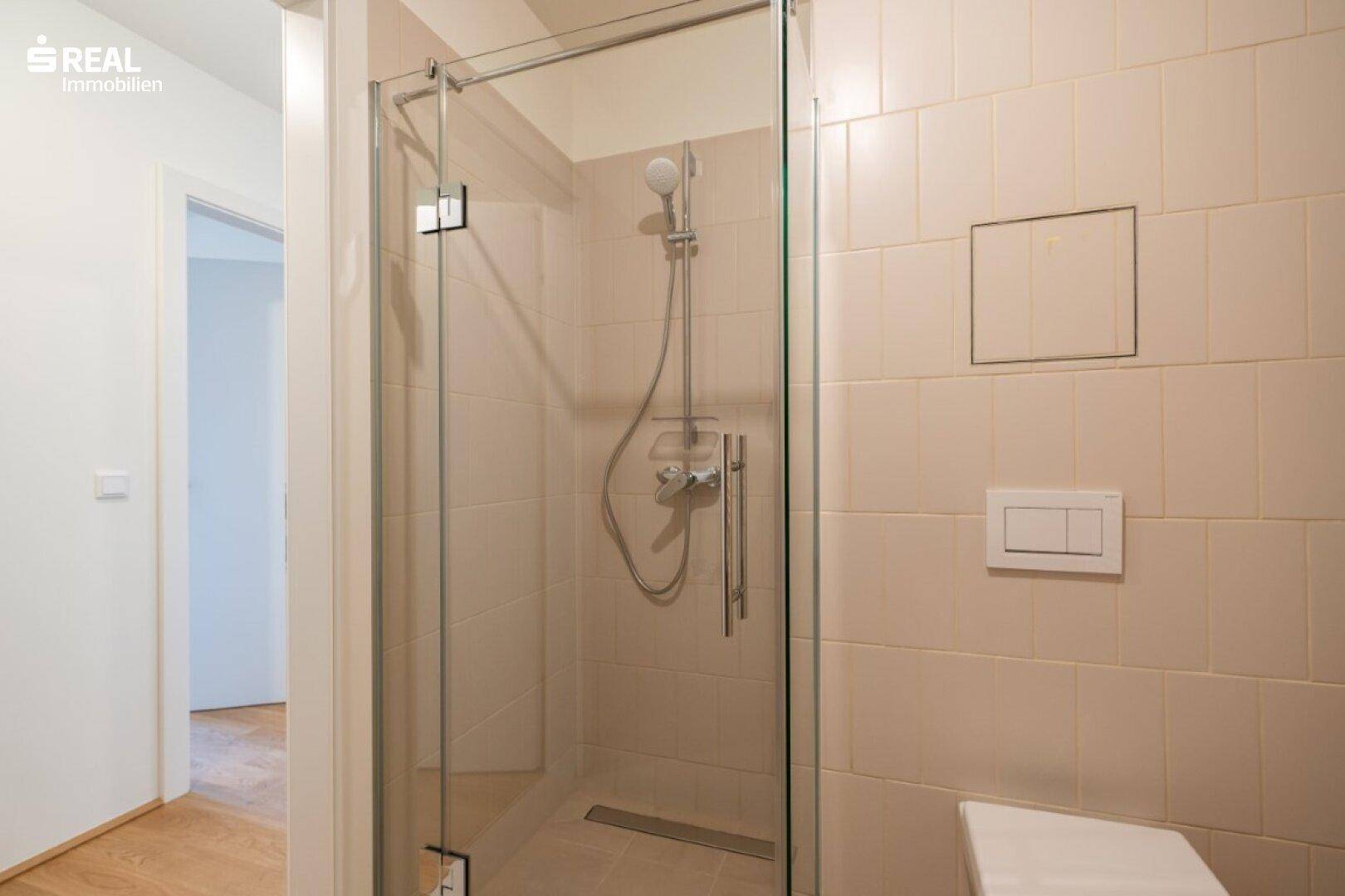 Zeitgemäßes Badezimmer mit geräumiger, ebenerdiger Dusche und hellen Fliesen.