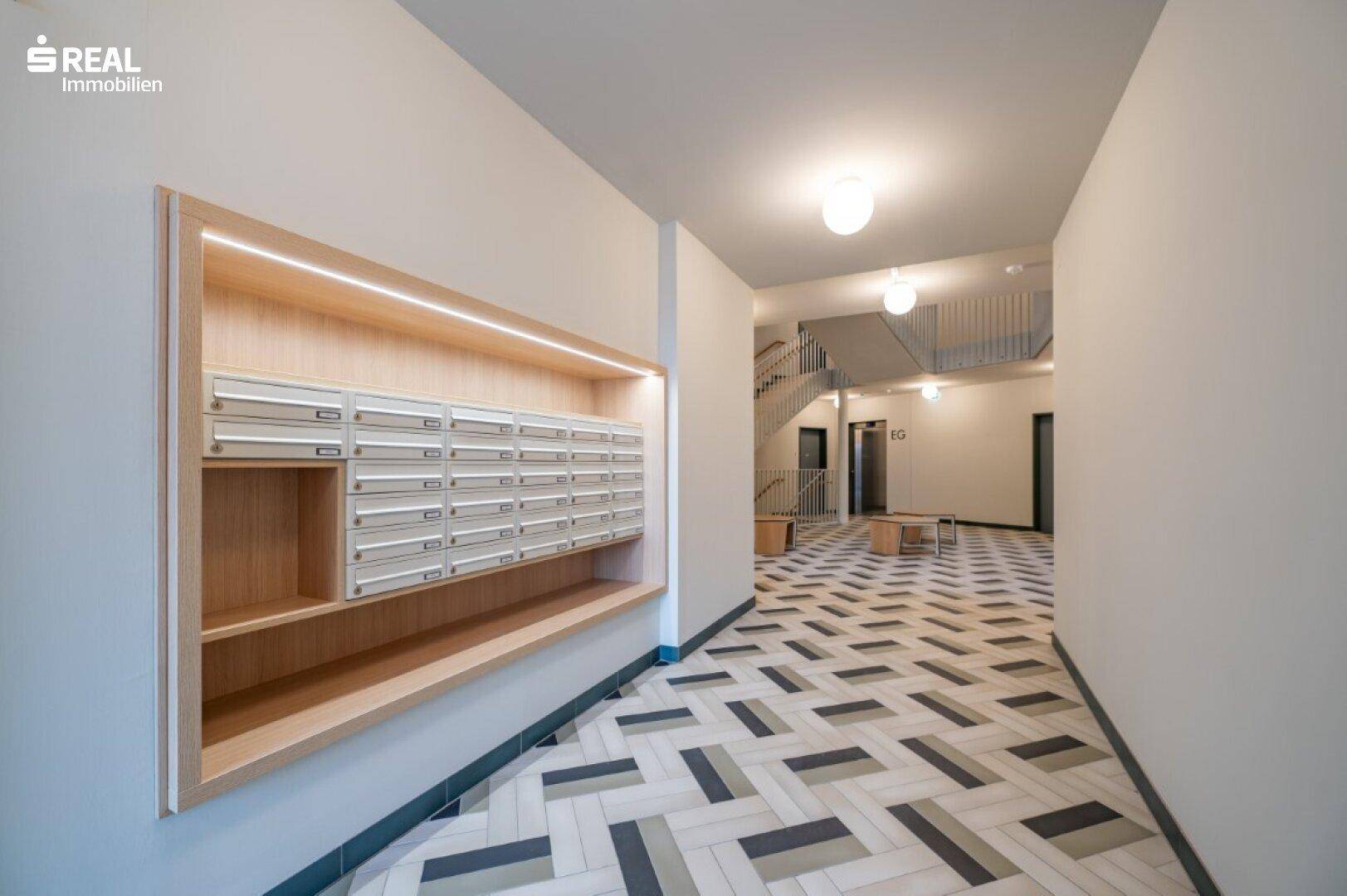 Moderner Eingangsbereich mit Briefkastenanlage und Treppenhaus in einem Mehrfamilienhaus.