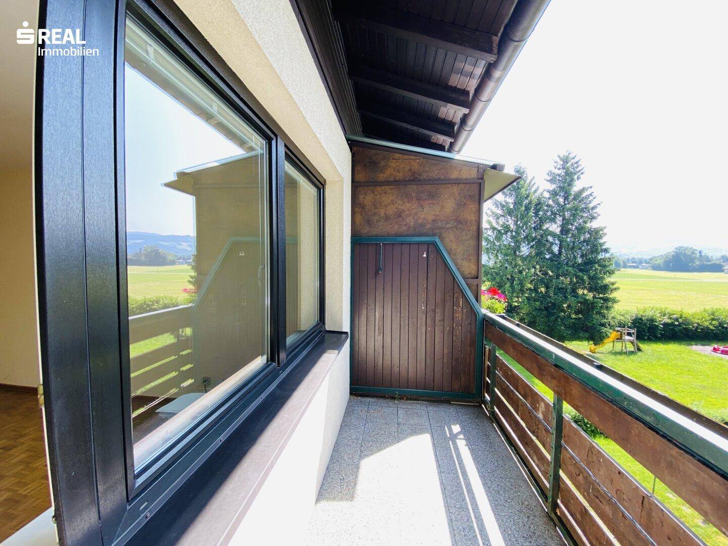 Heller Balkon mit weitem Blick ins Grüne und auf die umliegende Landschaft.
