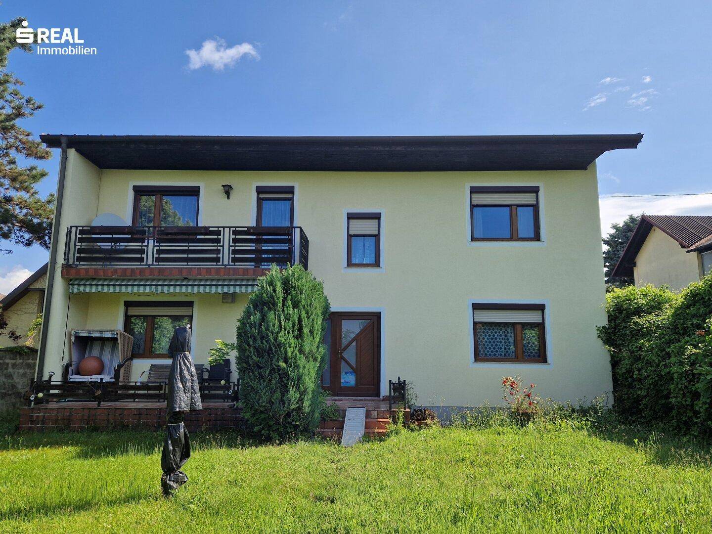 Ansicht des Hauses von außen mit Balkon, Terrasse und gepflegtem Vorgarten.