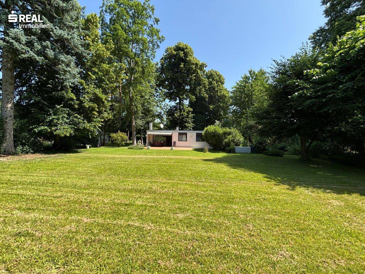 Weitläufiger Gartenbereich mit Rasenfläche und dem Haus im Hintergrund.