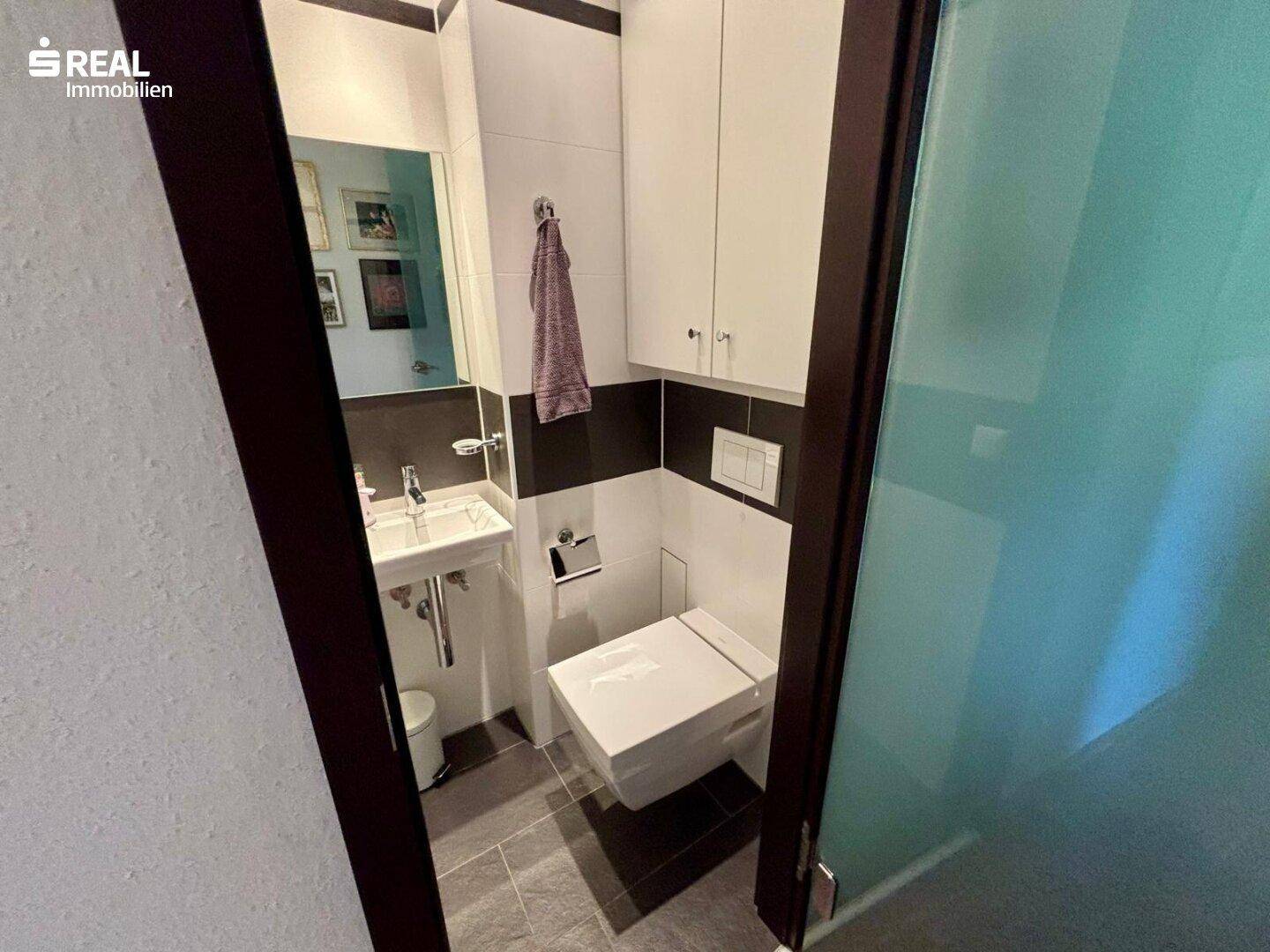 Separates Gäste-WC mit wandhängendem WC und kleinem Waschbecken.