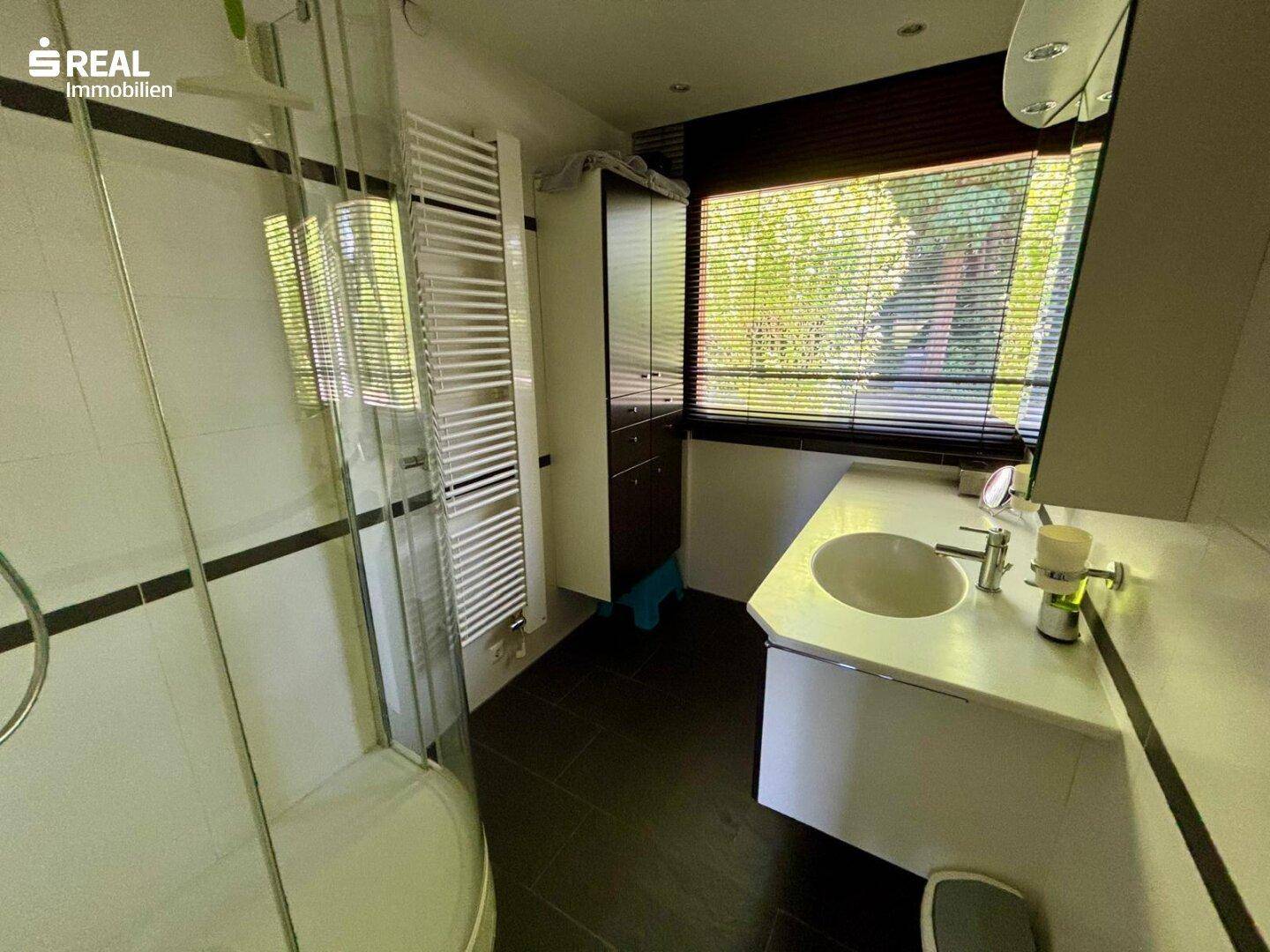 Modernes Badezimmer mit Dusche, Waschbecken und beheiztem Handtuchhalter.