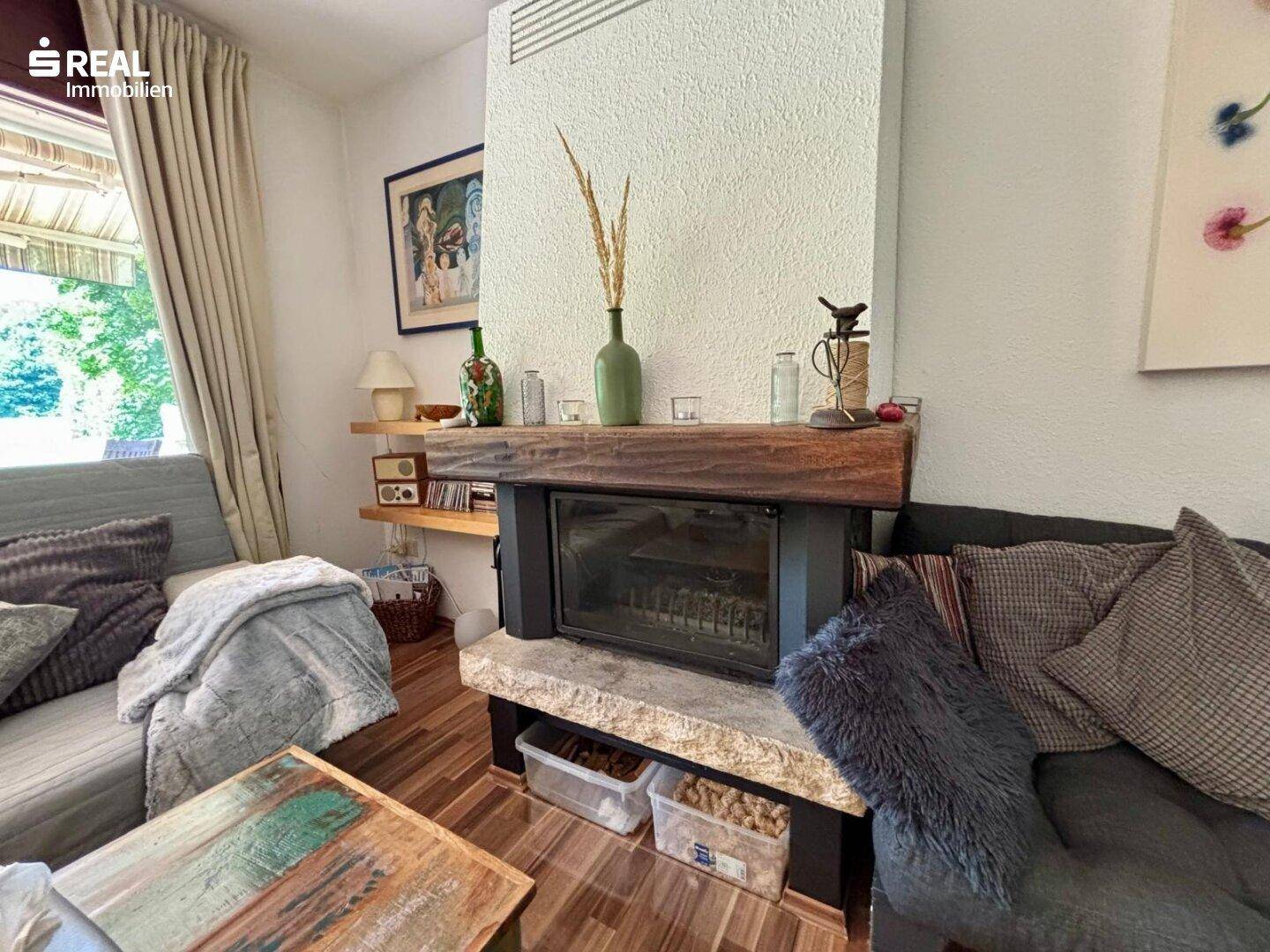 Detailansicht des Kamins mit Holzablage und rustikalem Charme im Wohnzimmer.