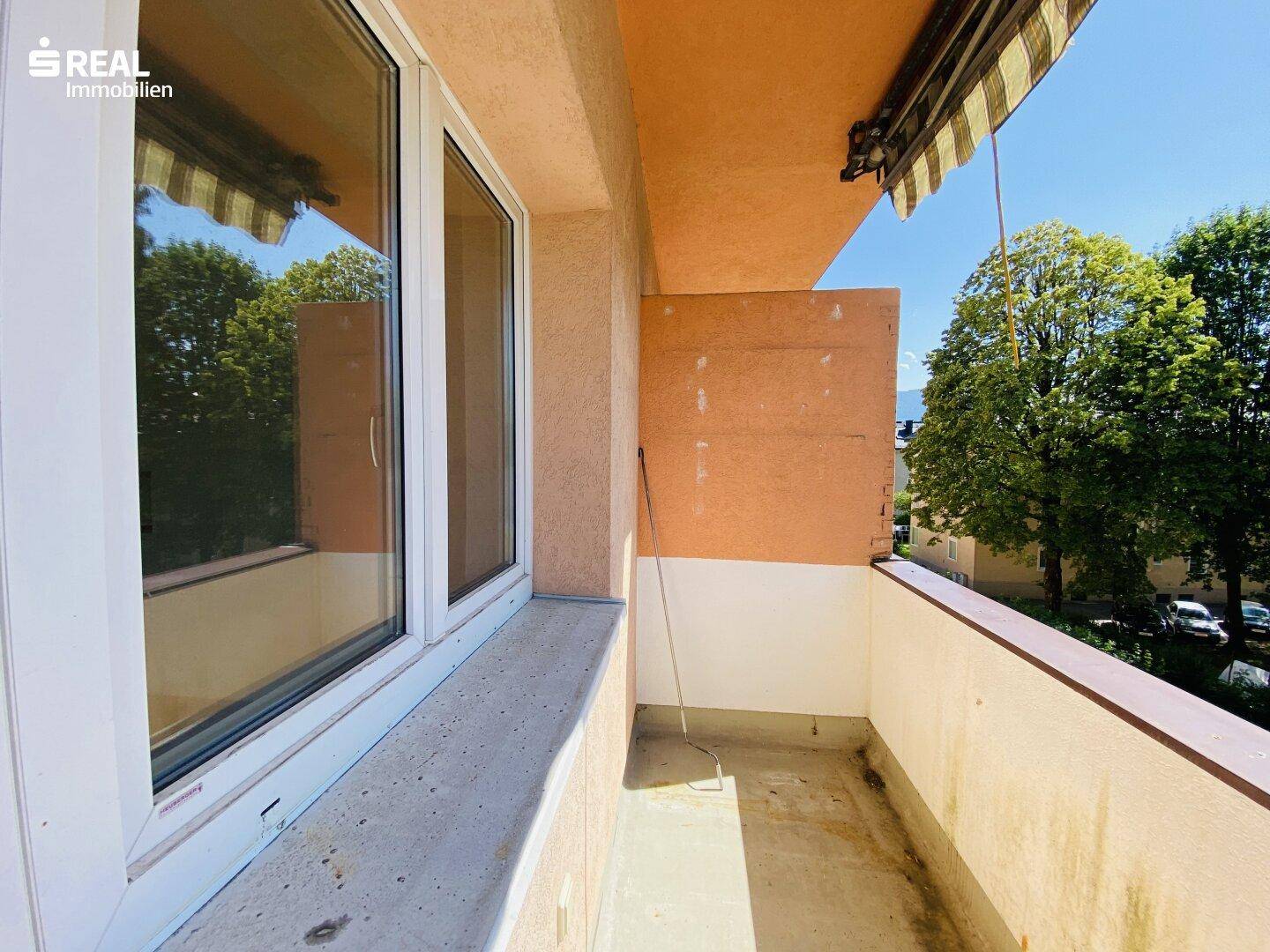Balkon mit Markise und Ausblick auf Bäume und die umliegende Bebauung.