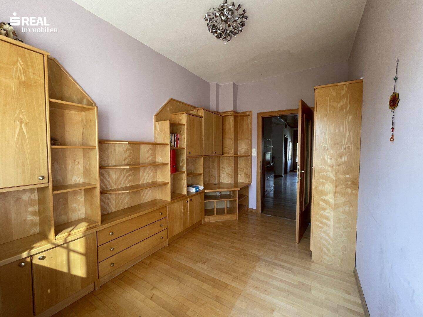Zimmer mit umfangreichen Holzregalen und Schränken, ideal als Büro oder Hobbyraum.