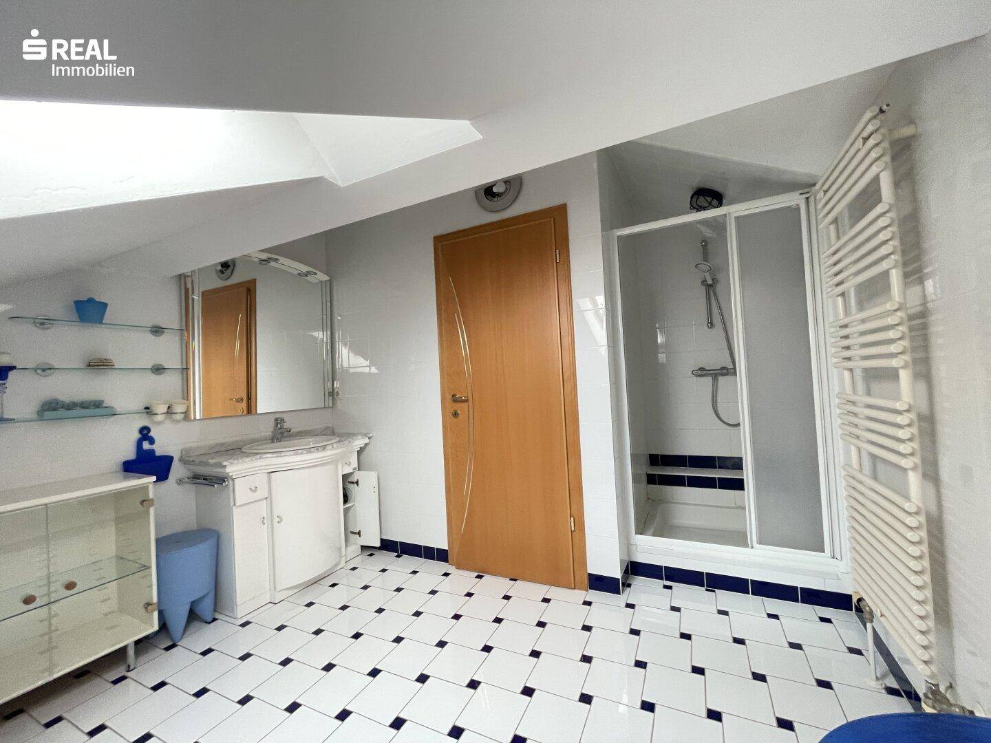 Badezimmer im Dachgeschoss mit Duschkabine, karierten Fliesen und beheiztem Handtuchhalter.