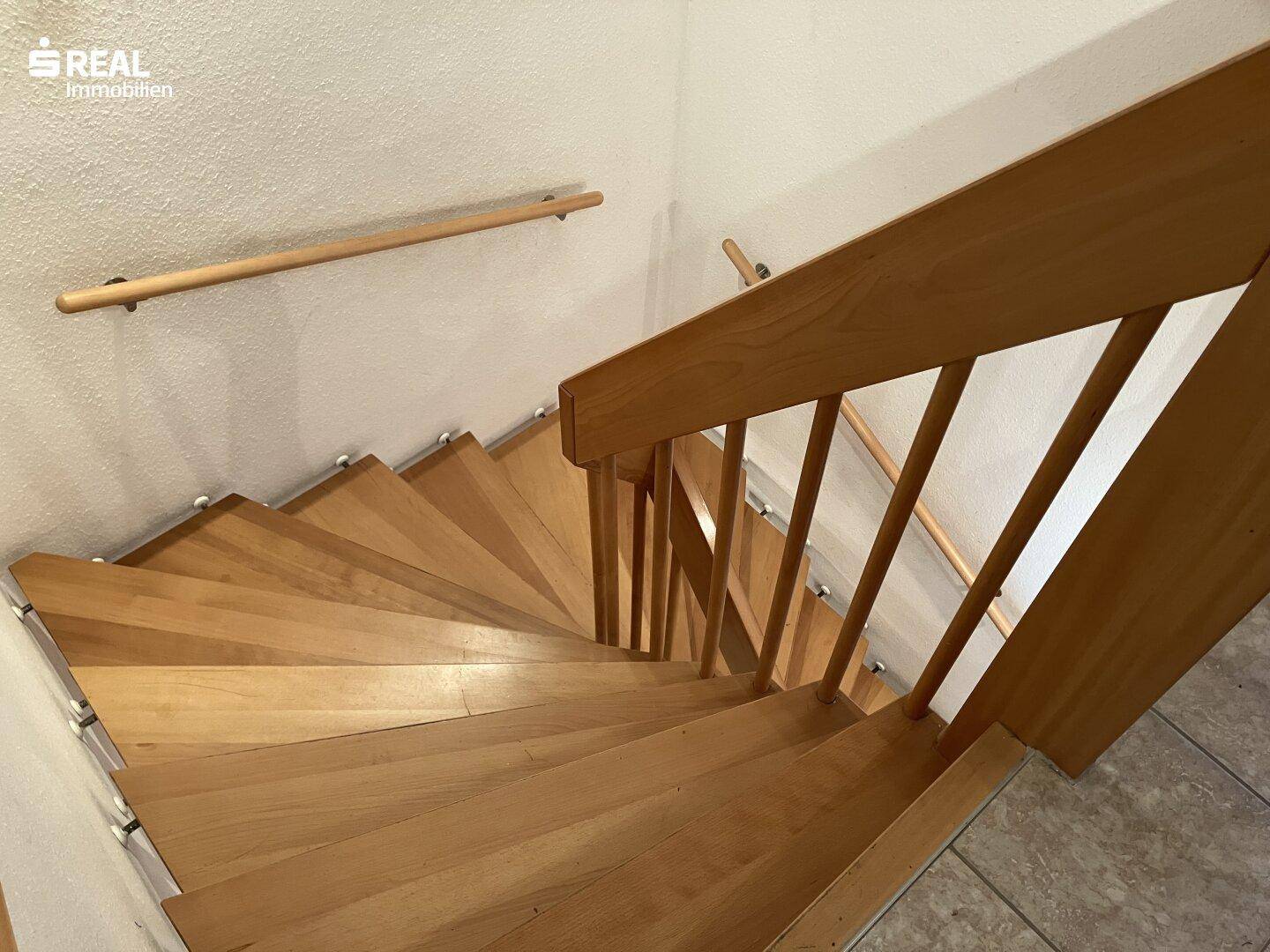 Ansicht von oben auf eine helle Holztreppe mit schlichtem Geländer und praktischem Handlauf.