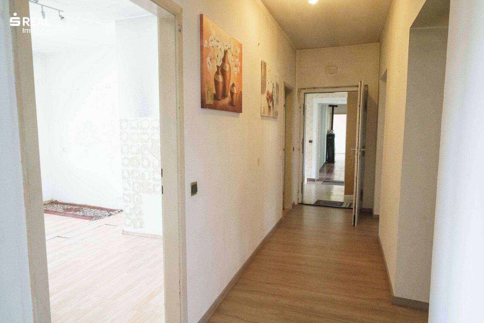 Langer Flur mit Laminatboden und mehreren Türen, der zu verschiedenen Räumen führt.