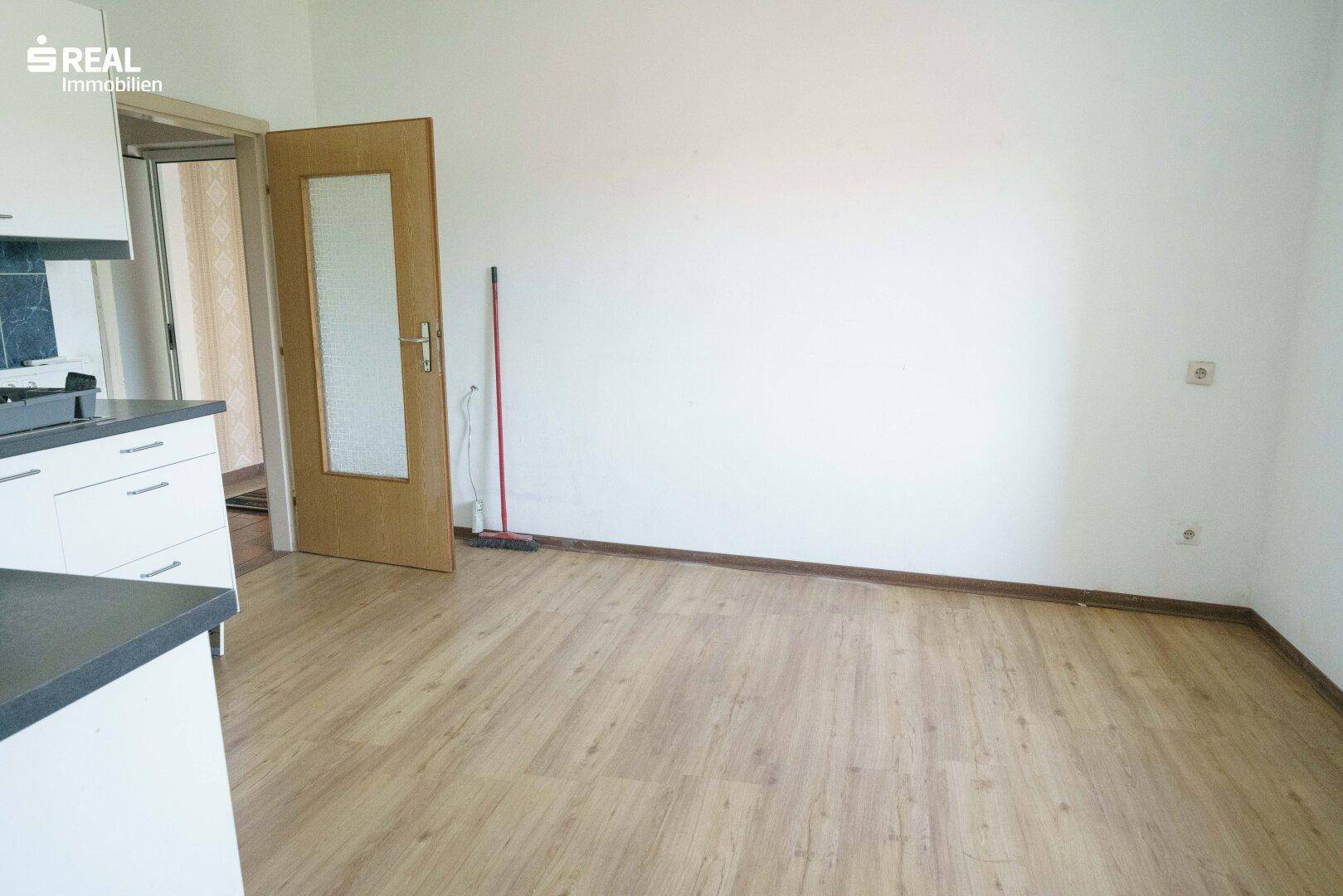 Offener Bereich mit Laminatboden neben der Küche, ideal für einen Essbereich.