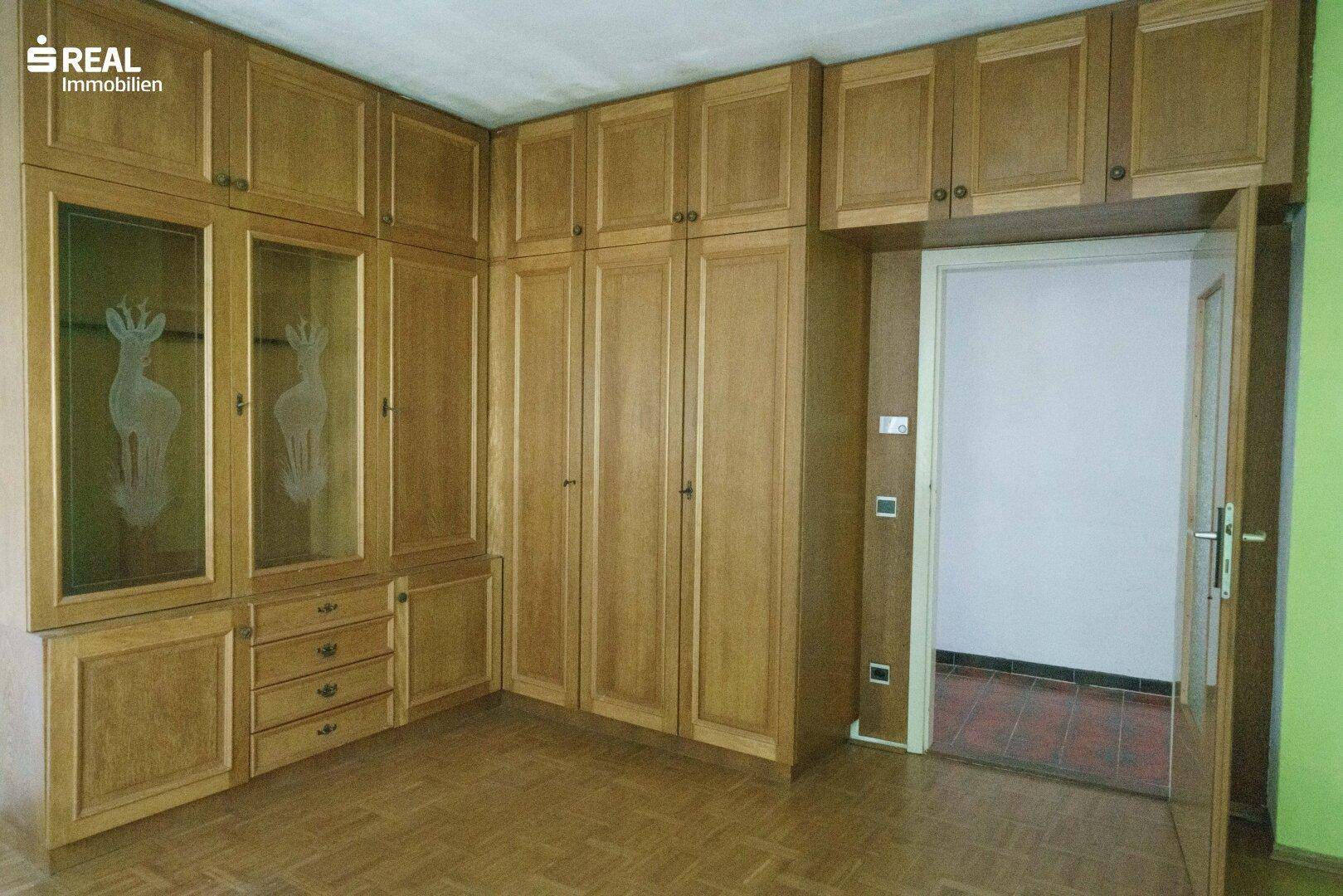 Zimmer mit umfangreichen Holzschränken und Laminatboden, bietet viel Stauraum.