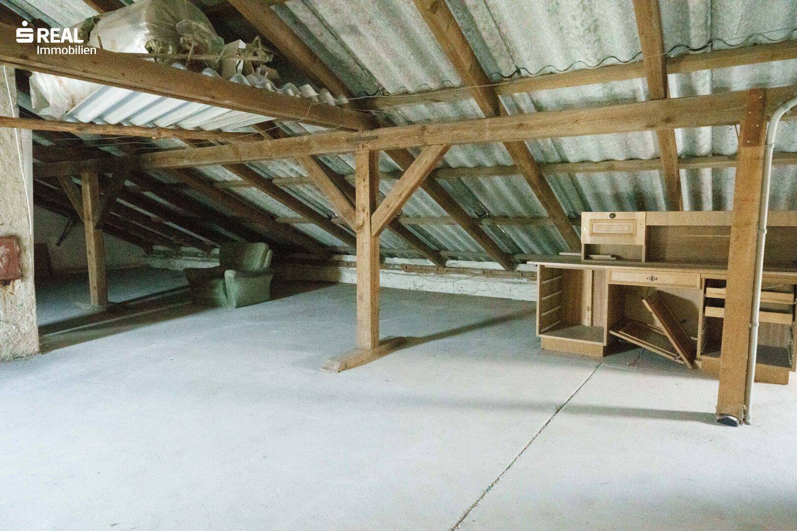 Geräumiger Dachboden mit sichtbaren Holzbalken und Betonboden, bietet Ausbaupotenzial.
