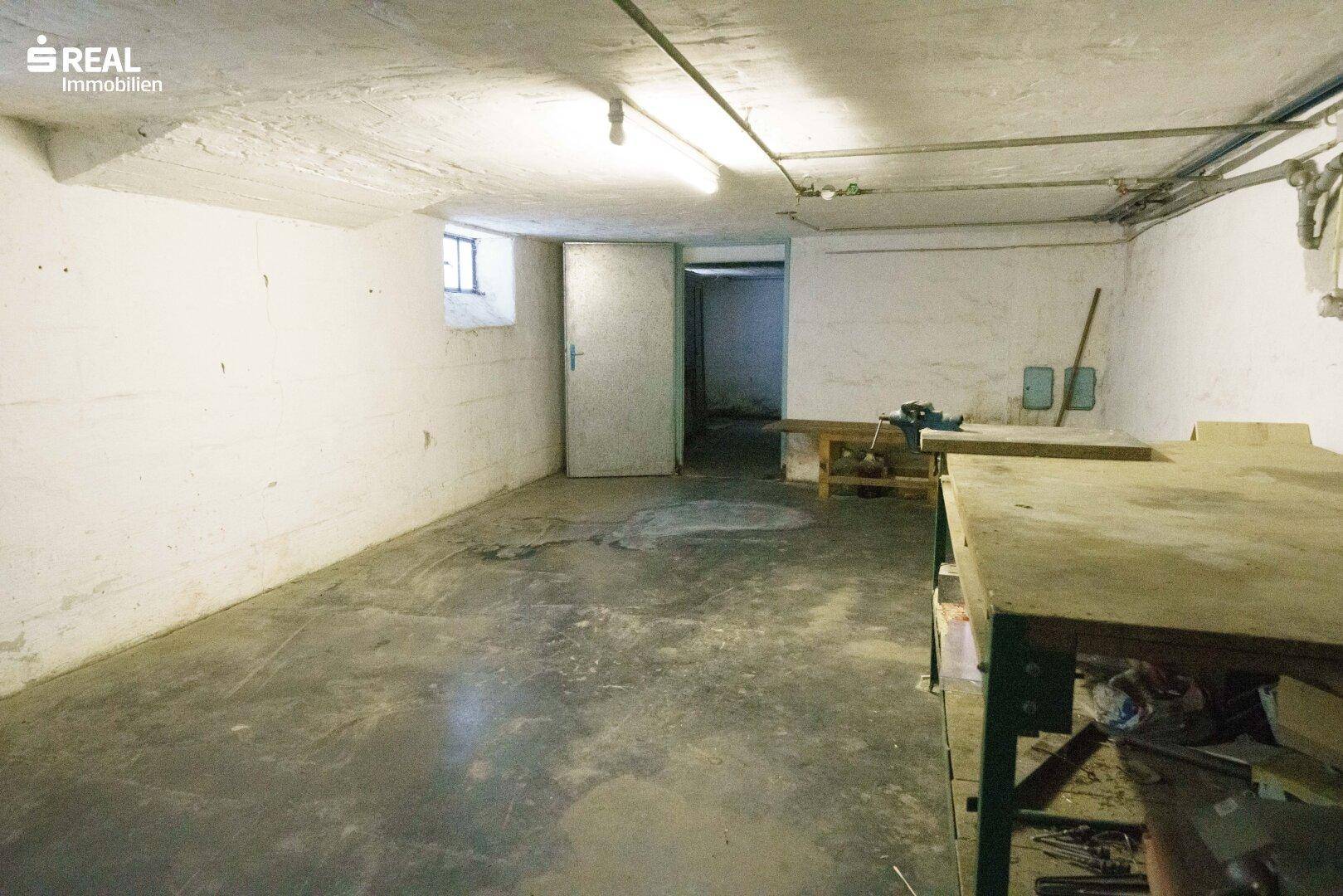 Großer Kellerraum mit Betonboden und Werkbänken, ideal als Hobbyraum oder Lager.