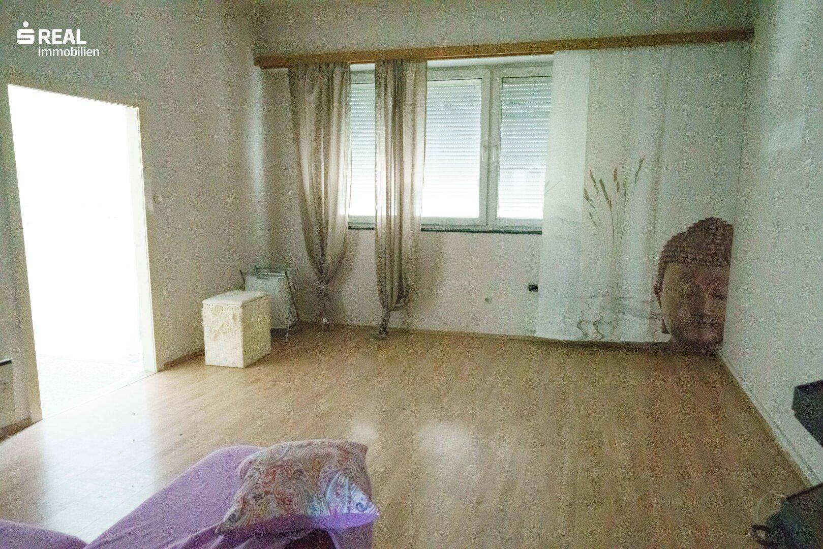 Helles Zimmer mit Laminatboden und Vorhängen, bietet eine gemütliche Atmosphäre.