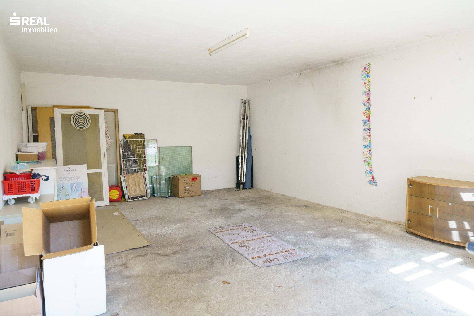 Großer Abstellraum mit Betonboden und verschiedenen Gegenständen, bietet viel Stauraum.