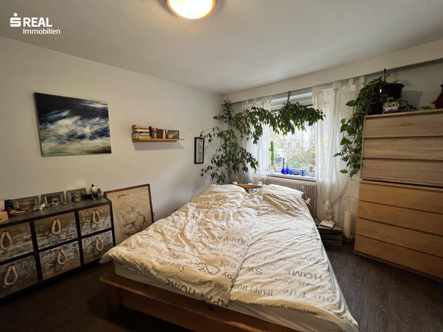 Gemütliches Schlafzimmer mit großem Bett, Holzmöbeln und Blick ins Grüne.
