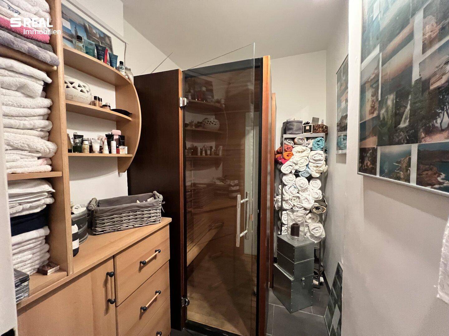 Kleiner Wellnessbereich mit Sauna, Regalen und Stauraum für Handtücher.