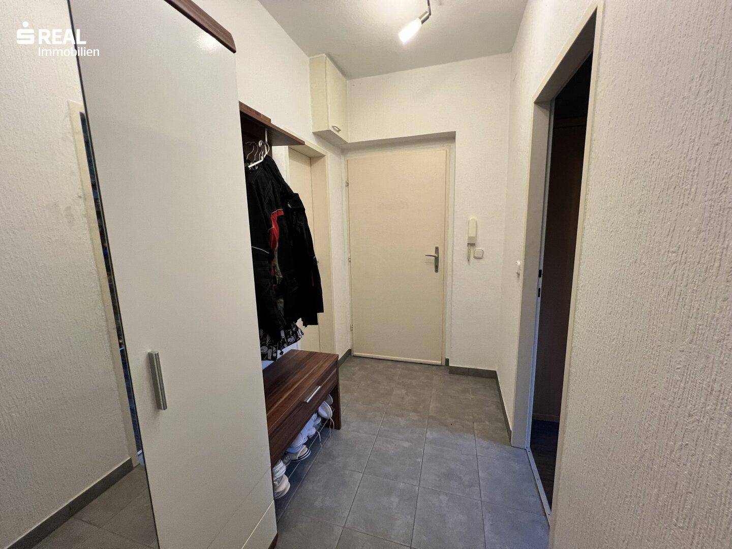 Eingangsbereich mit Garderobe, Schuhbank und Fliesenboden.