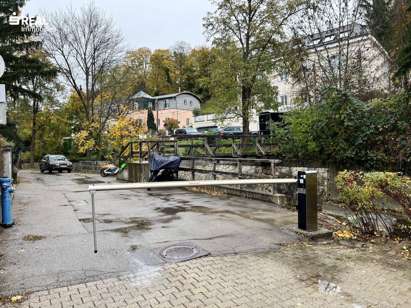 Zufahrtsstraße mit Schranke und umliegender Vegetation.