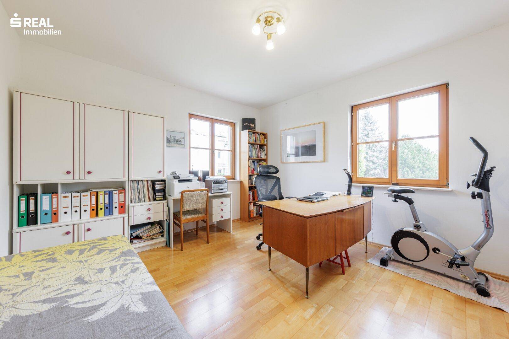 Helles Arbeitszimmer mit Parkettboden, großem Schreibtisch und Einbauschränken, auch als Gästezimmer nutzbar.