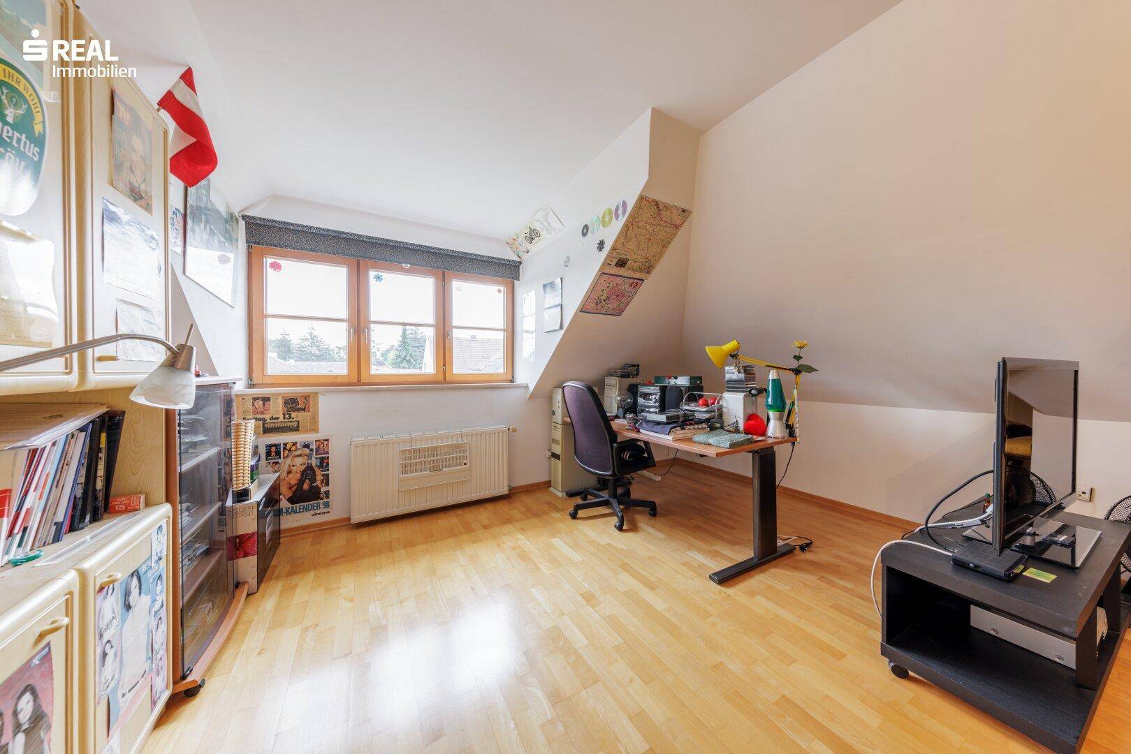 Funktionaler Dachbodenraum mit Schreibtisch, Stauraum und Fenster, ideal als Arbeits- oder Jugendzimmer.
