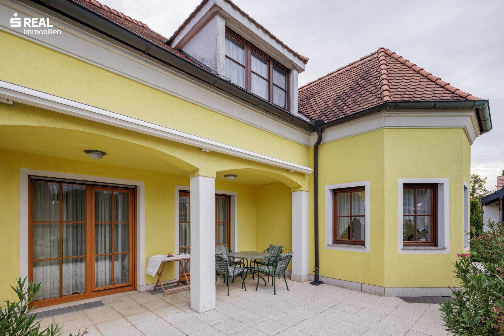 Überdachte Terrasse mit Sitzgelegenheiten, ideal für entspannte Stunden im Freien, mit Zugang zum Garten.