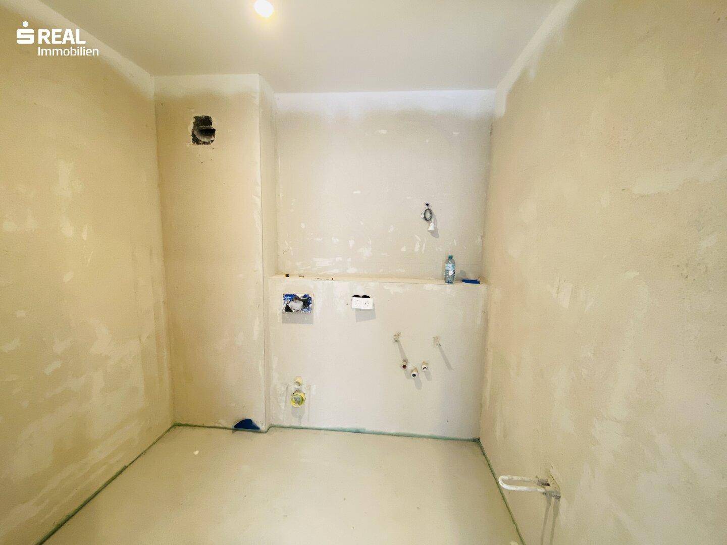 Unfertiges Badezimmer mit sichtbaren Sanitäranschlüssen, bereit für den Ausbau.