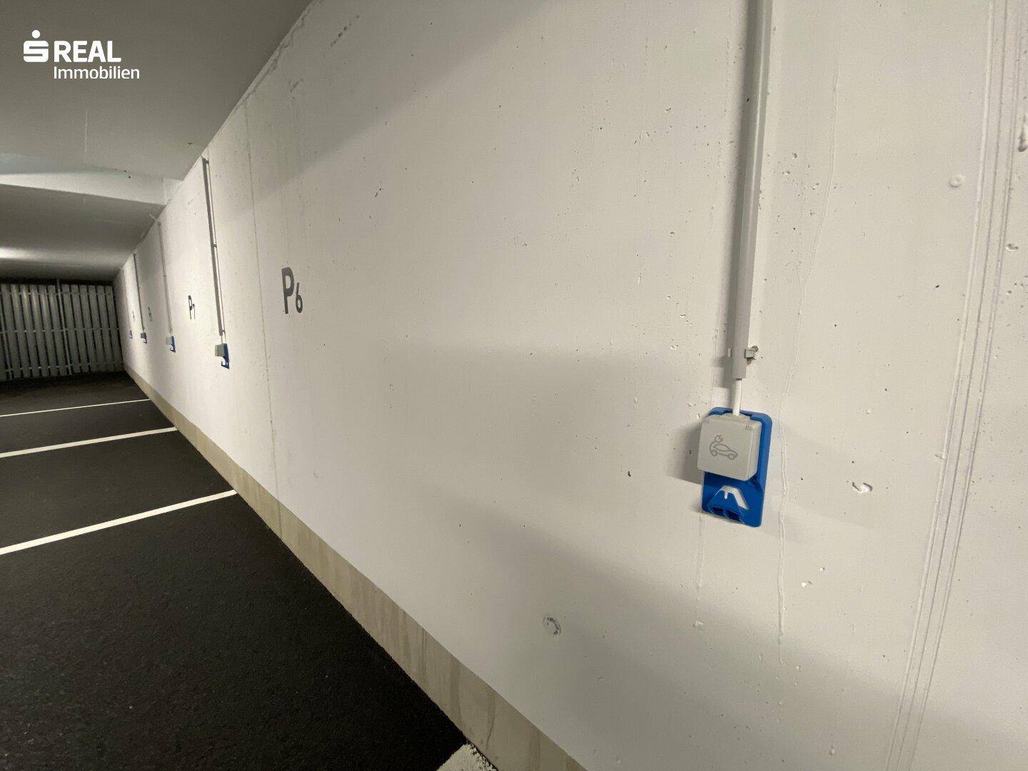 Saubere und gut beleuchtete Tiefgarage mit markierten Parkplätzen in einem modernen Gebäude.