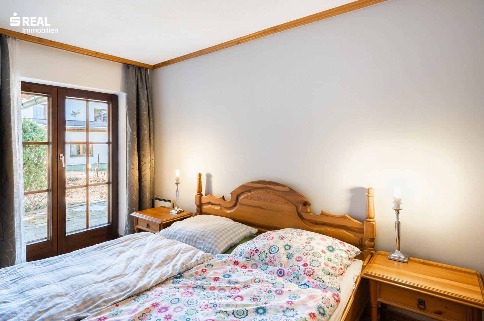 Helles Schlafzimmer mit traditionellem Holzbett und direktem Zugang zum Gartenbereich.