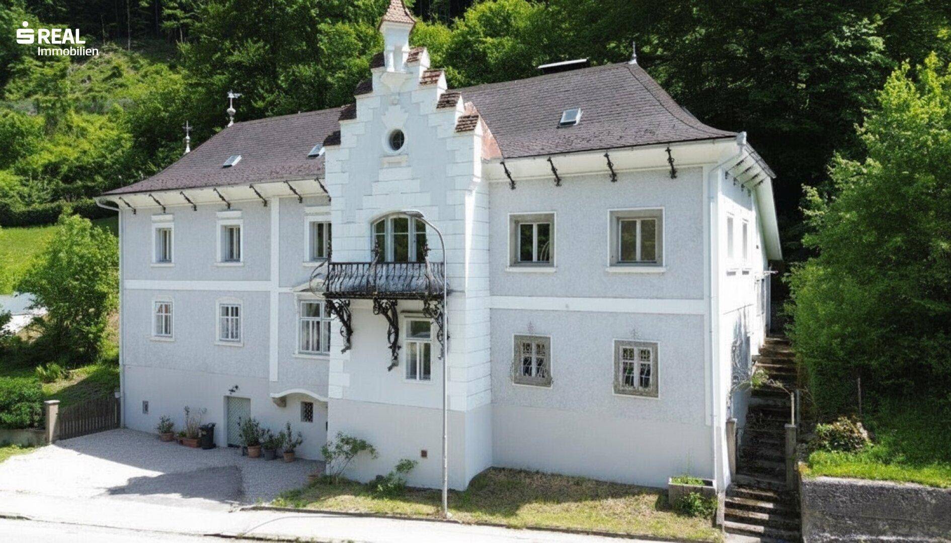 Ansicht der historischen Fassade mit dekorativen Elementen und einem kleinen Balkon über dem Eingangsbereich.