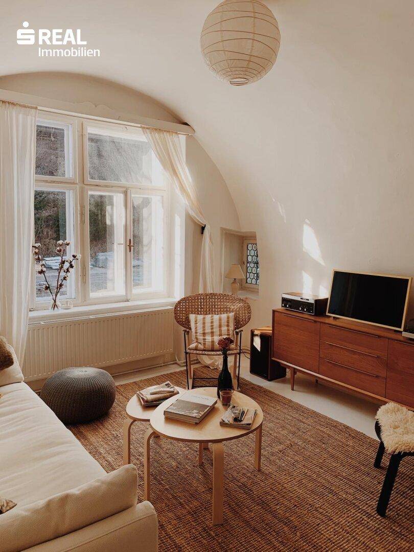 Wohnzimmer mit gewölbter Decke, großen Fenstern und einer Mischung aus modernen und Vintage-Möbeln.