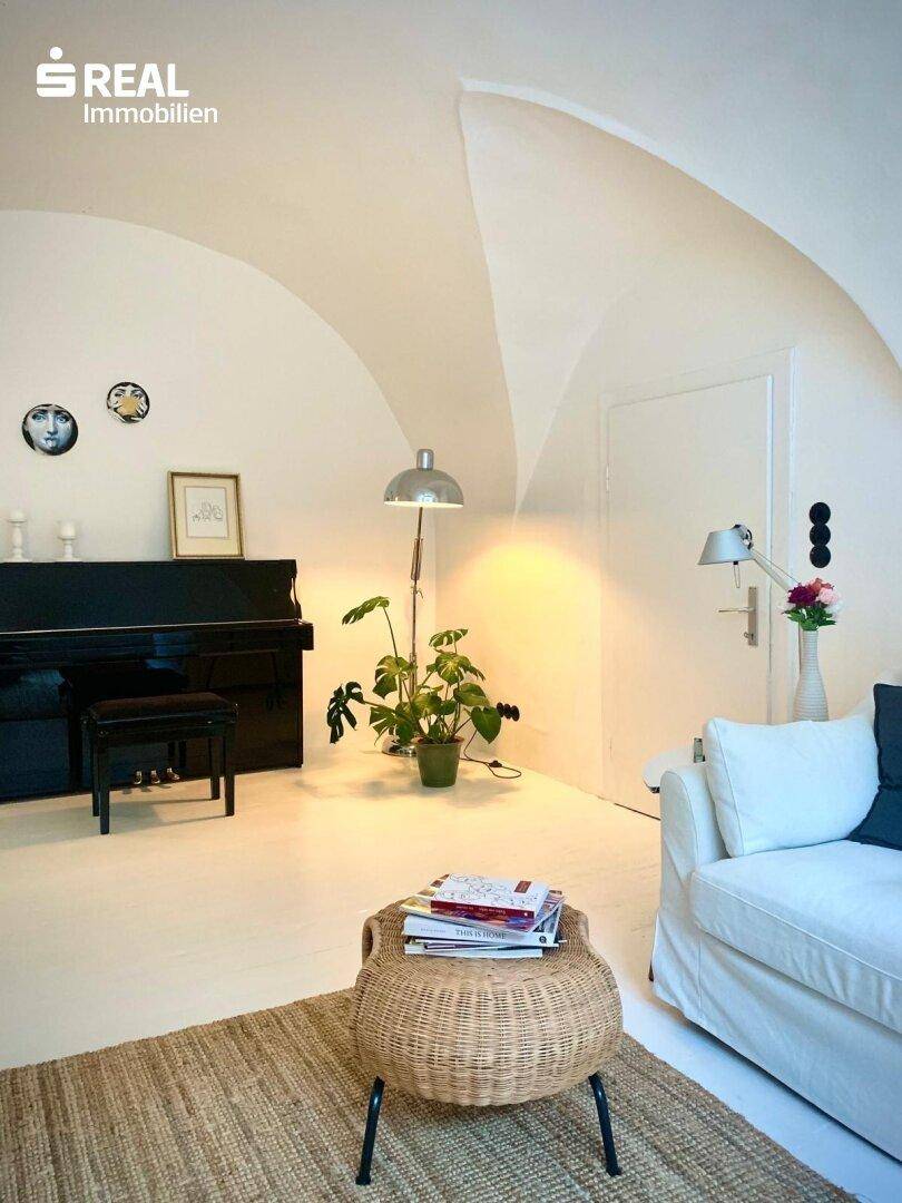 Heller Wohnraum mit Klavier, gewölbter Decke und schlichtem, elegantem Design.