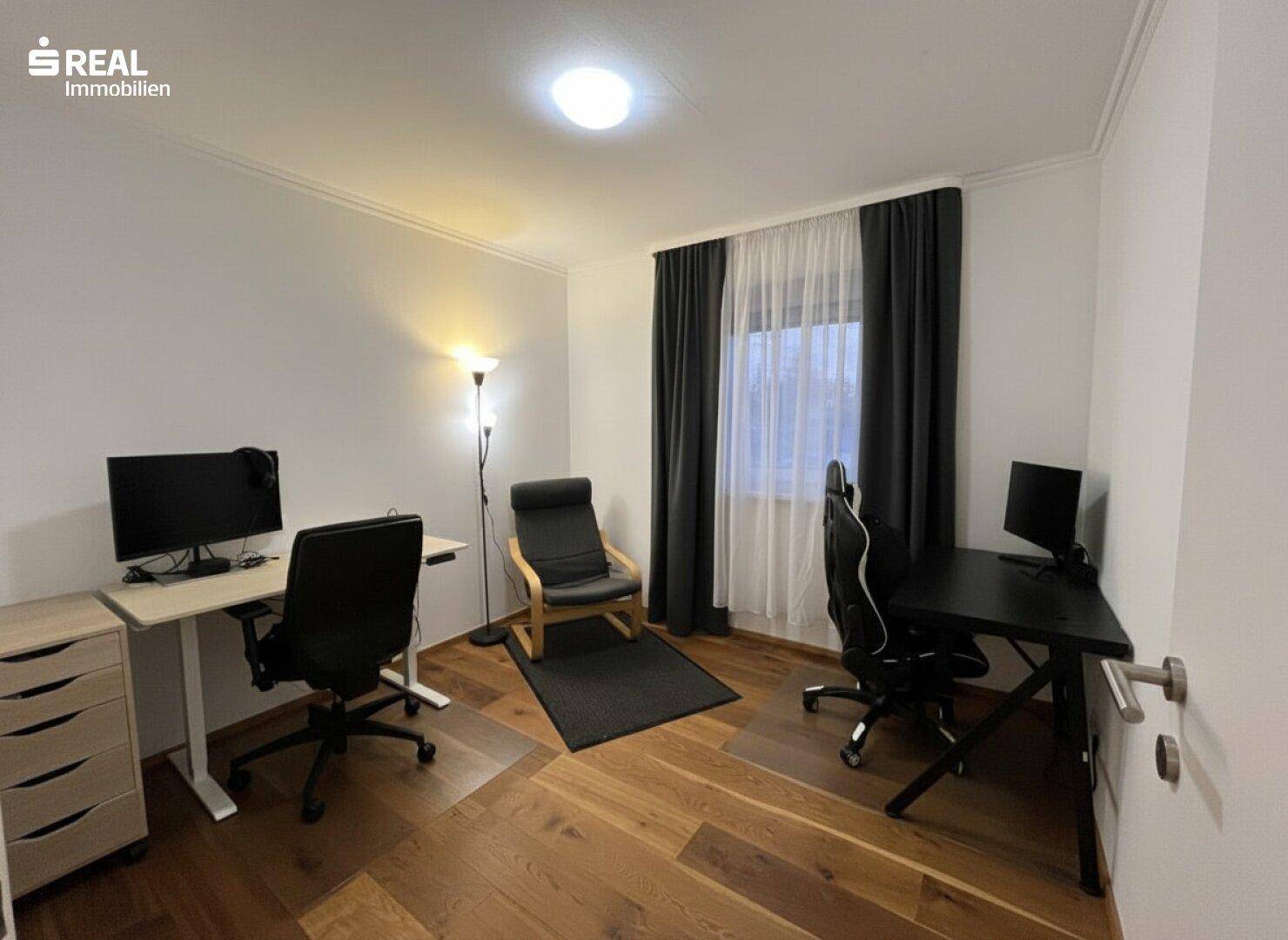 Helles Arbeitszimmer mit Holzboden und zwei Schreibtischen.