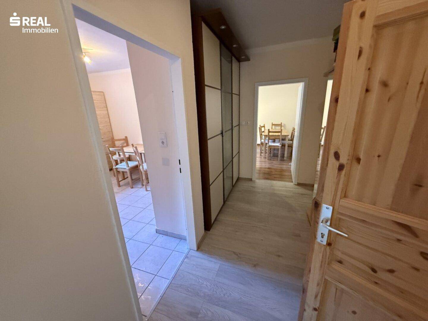 Heller Flur mit Holzfußboden und integrierten Schränken, der zu weiteren Räumen führt.