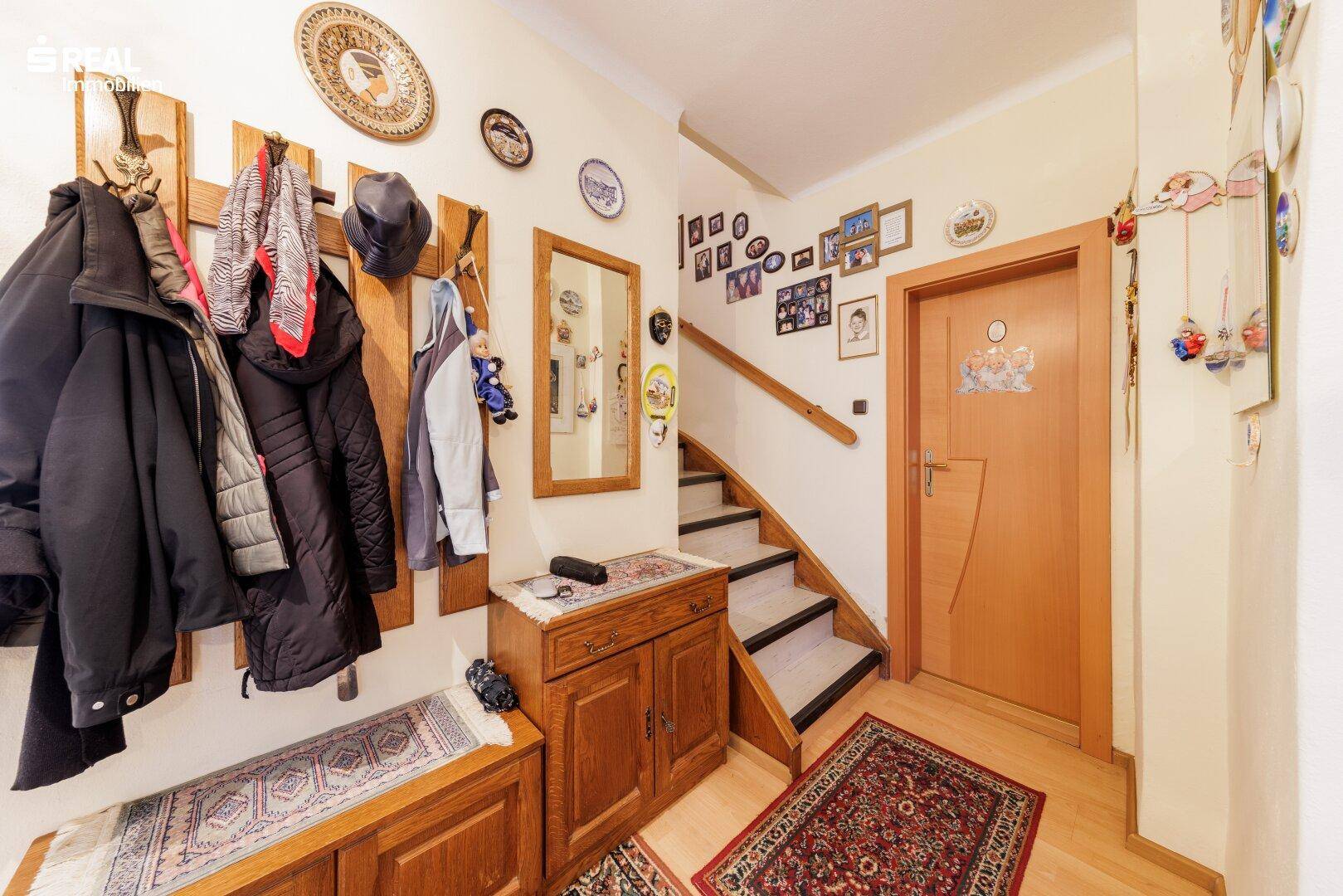 Gemütlicher Flur mit Garderobe, Spiegel und Treppenaufgang, dekoriert mit persönlichen Bildern.