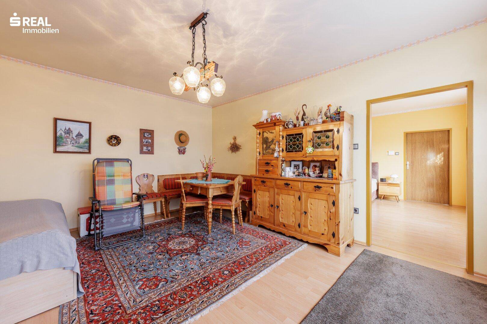 Schlafzimmer mit Einzelbett, Teppich und traditionellen Holzmöbeln, hell und funktional.