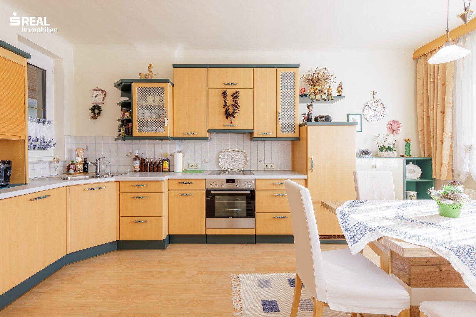 Geräumige Küche mit Holzfronten, integrierten Geräten und einem Essbereich am Fenster.