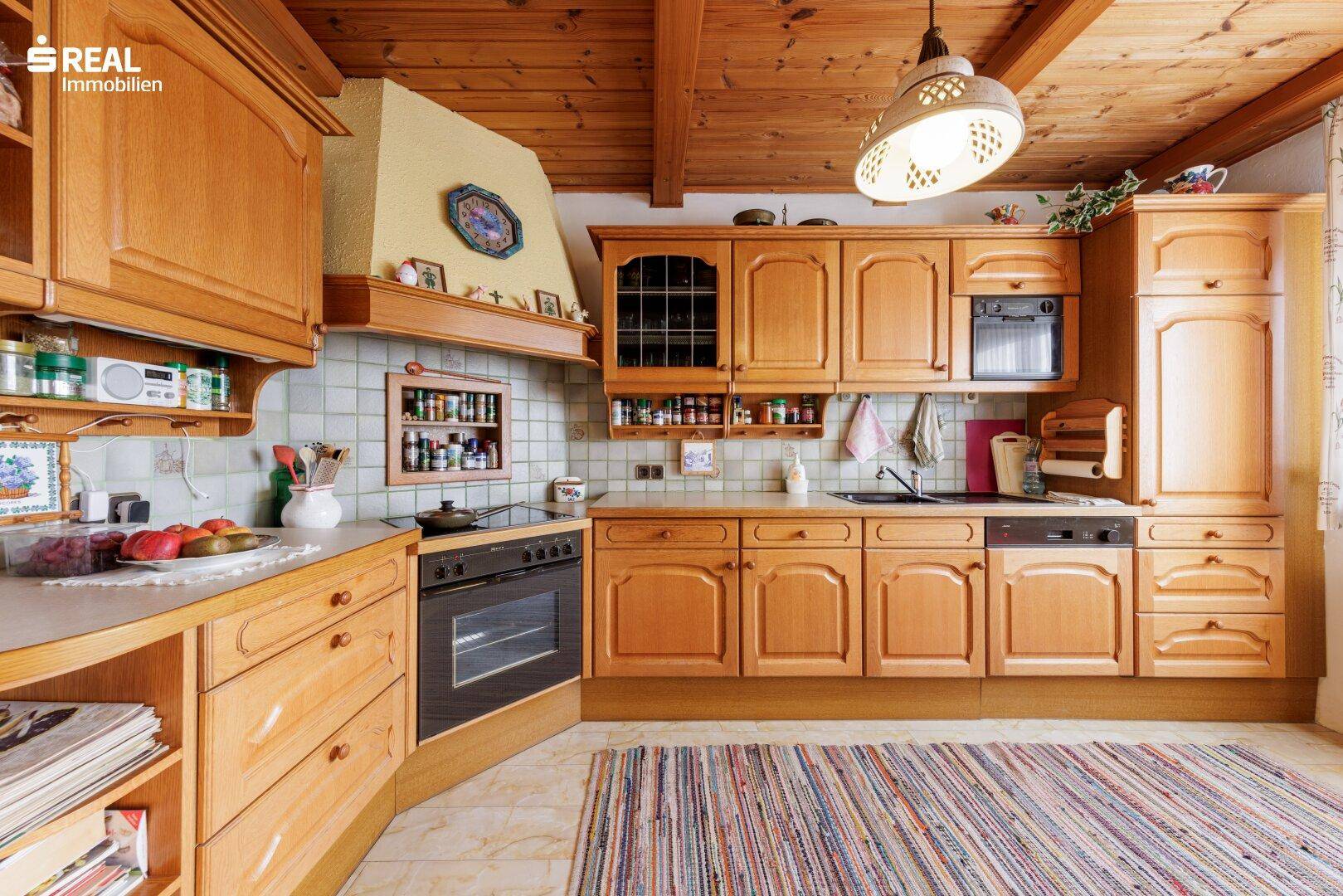 Rustikale Holzküche mit Einbaugeräten, Fliesenboden und Holzdecke, gemütlich eingerichtet.