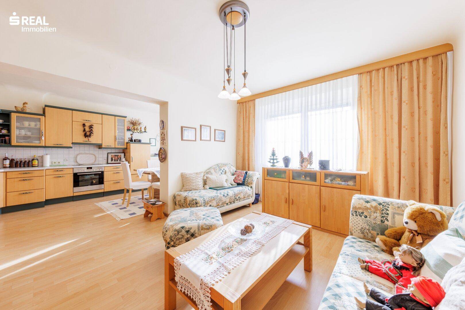 Gemütlicher Wohnbereich mit Laminatboden und Blick auf die angrenzende Küche, ideal für Familien.
