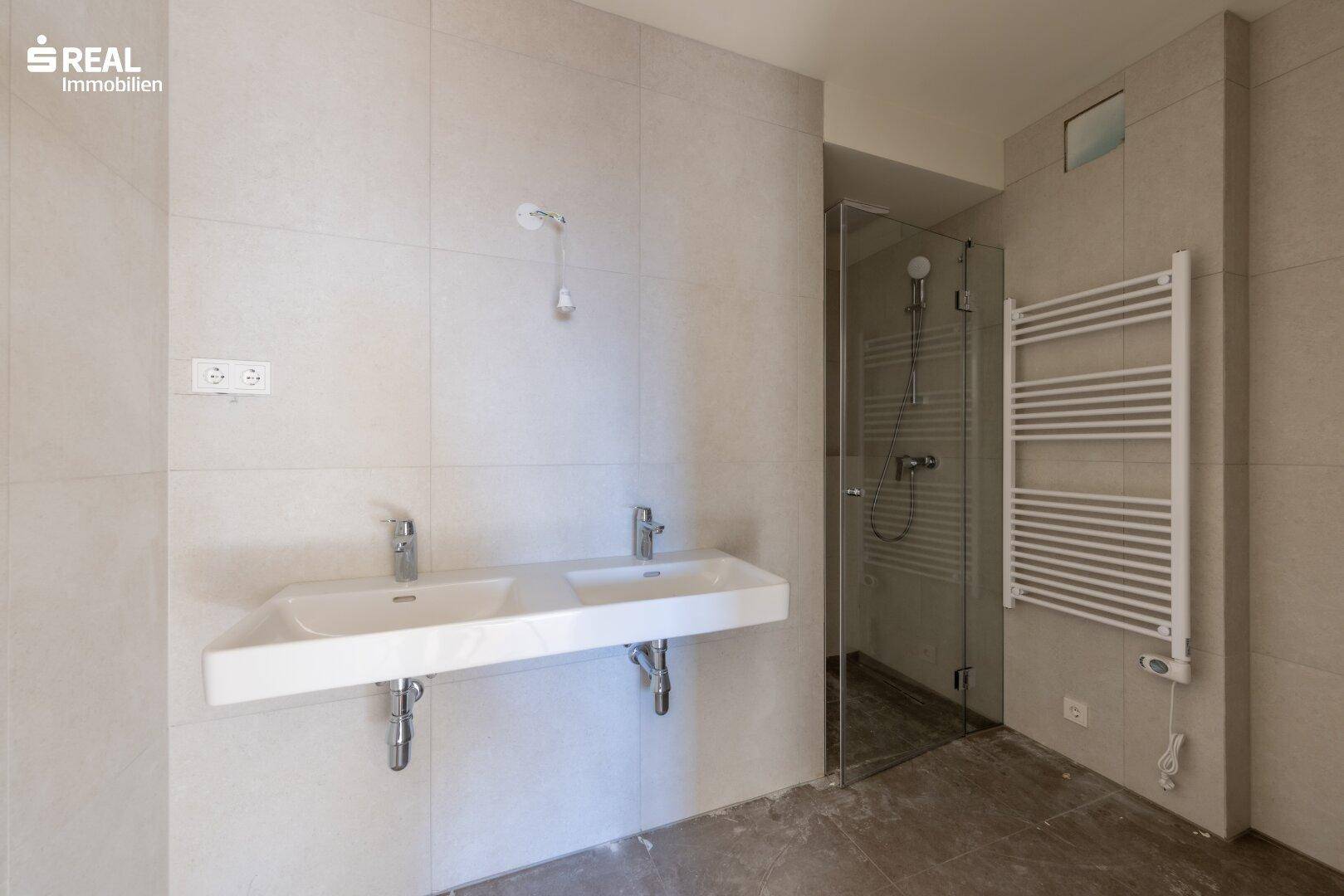 Modernes Badezimmer mit Doppelwaschbecken, großer Dusche und beheiztem Handtuchhalter.
