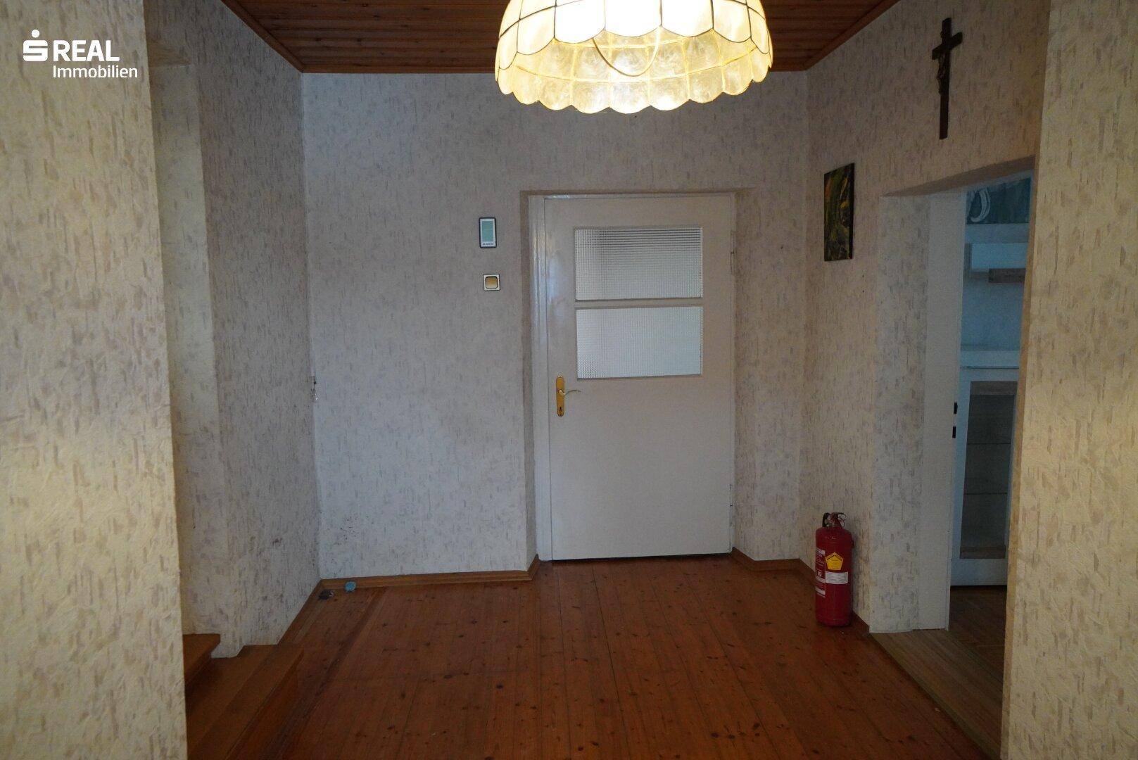 Eingangsbereich mit Holzdecke, Holzboden und einer weißen Tür.