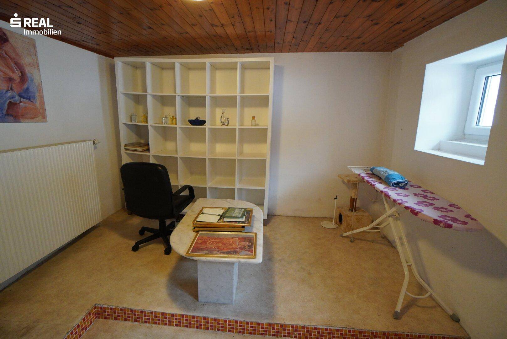 Vielseitiger Raum mit großem Regal, Schreibtisch und Fenster, ideal als Büro oder Hobbyraum.