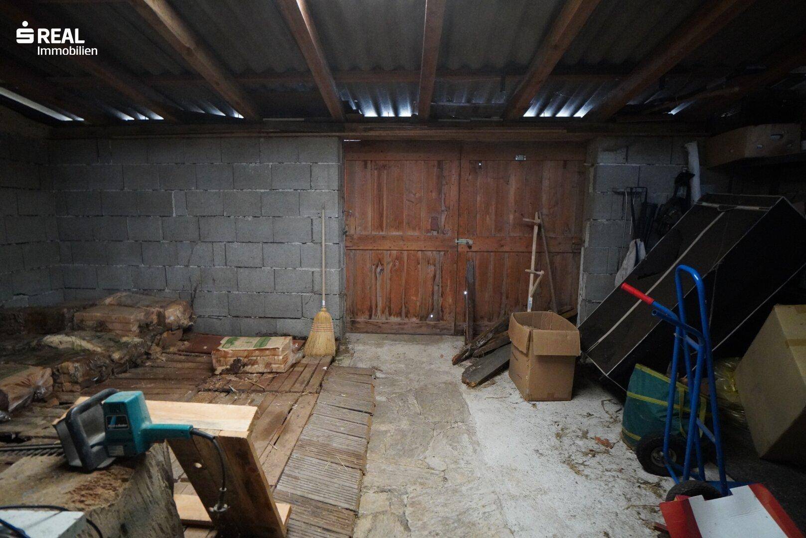 Geräumiger Lagerraum oder Werkstatt mit Holztüren und Betonwänden.