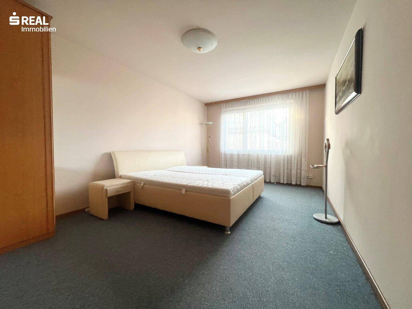 Gemütliches Schlafzimmer mit Doppelbett, Teppichboden und Fenster für natürliches Licht.