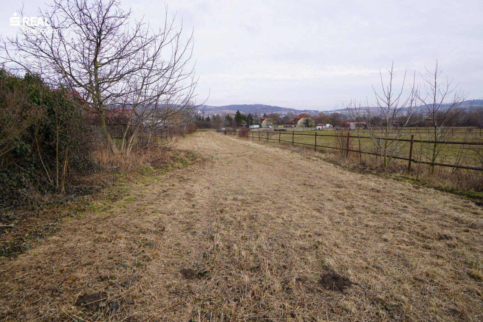 Langes, schmales Grundstück mit Blick auf die ländliche Umgebung und entfernte Bebauung.