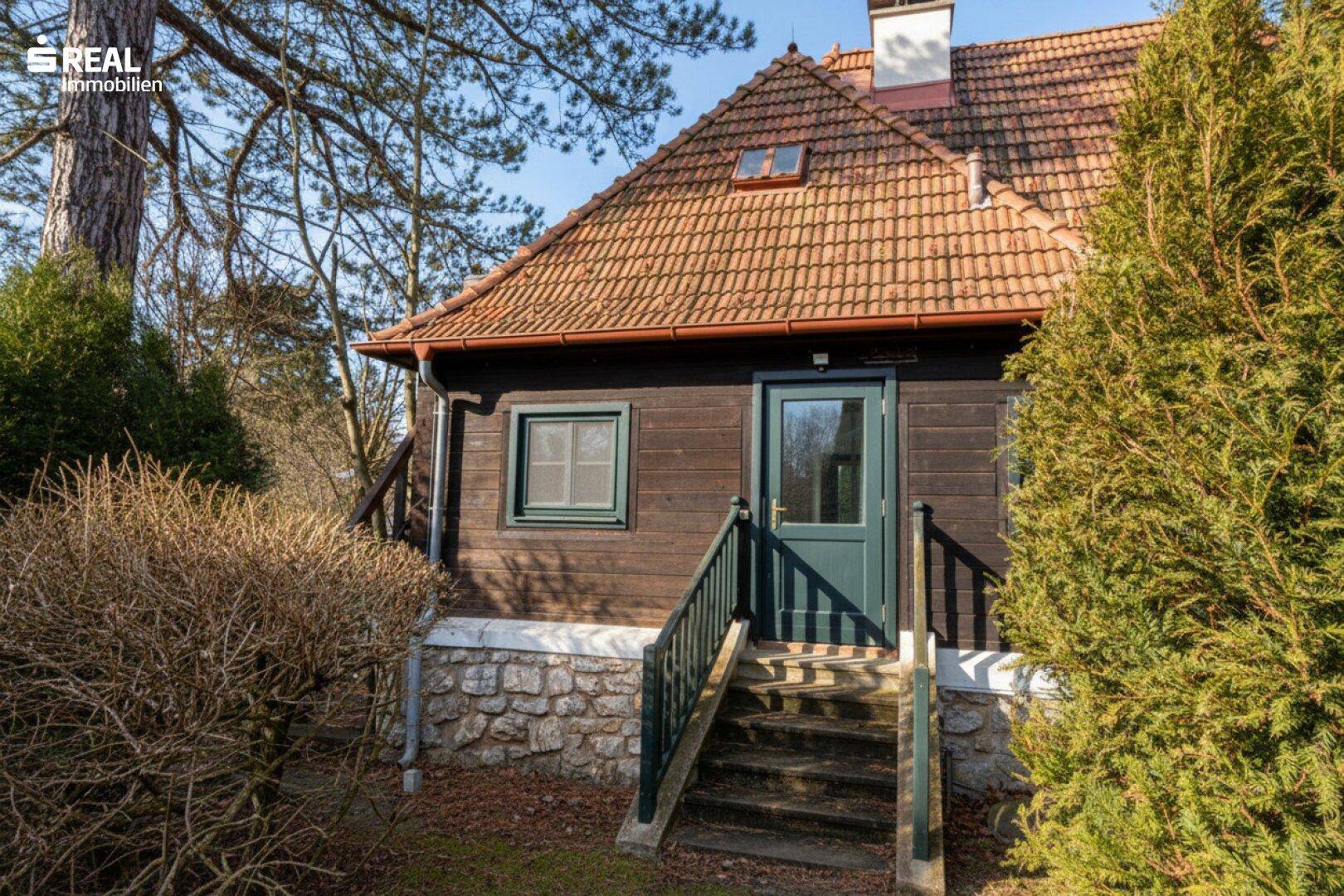 Nahaufnahme der Holzfassade des Hauses mit Ziegeldach und Eingangsbereich.